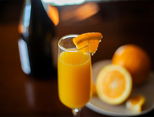 a glass of orange juice with a slice of orange on top
